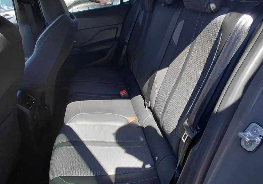 Vue intérieure des sièges arrière gris d'une Peugeot 308 2025, avec ceinture de sécurité et porte ouverte côté droit.