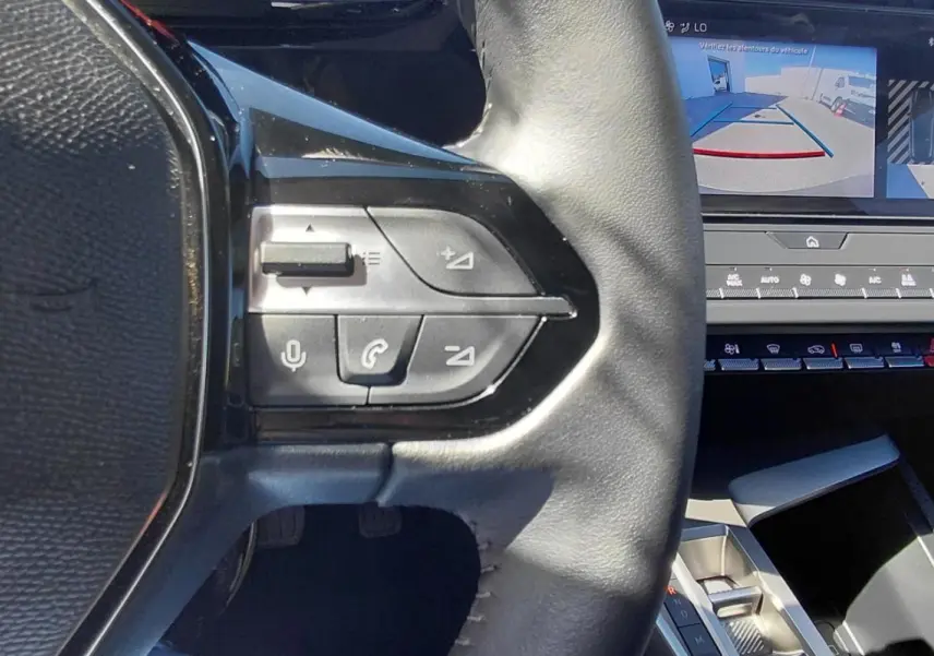 Gros plan sur le volant et l’écran central affichant la caméra de recul dans l’habitacle gris de la Peugeot 308 2025.