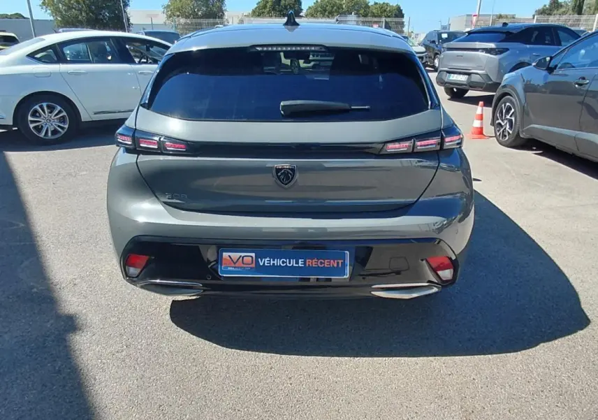 Vue arrière d'une Peugeot 308 gris métallisé 2025 avec feux LED et double sortie d'échappement visible en parking.