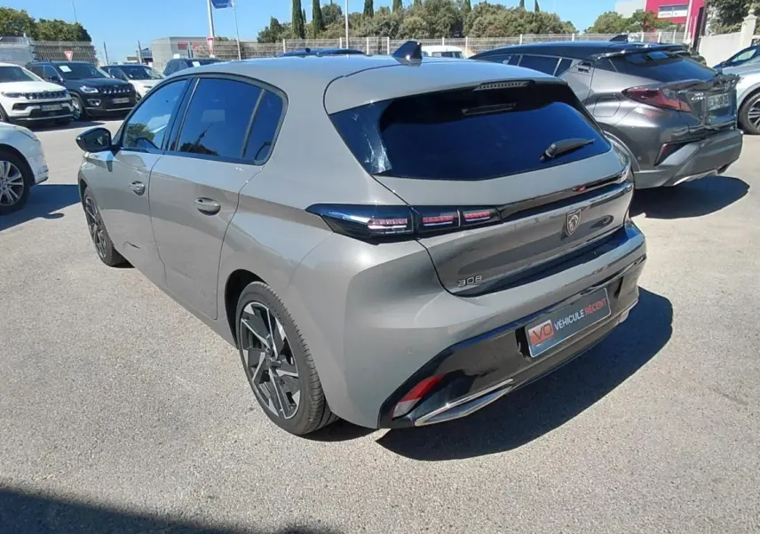 Vue 3/4 arrière droite d’une Peugeot 308 gris métallisé 2025 avec feux arrière LED et jantes alliage noires.
