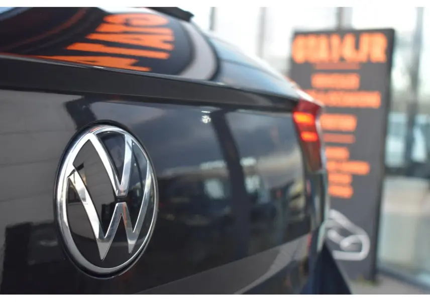 Vue rapprochée arrière gauche du Volkswagen T-Roc 2025 en noir Grenadilla avec logo VW et feu arrière LED rouge clair.