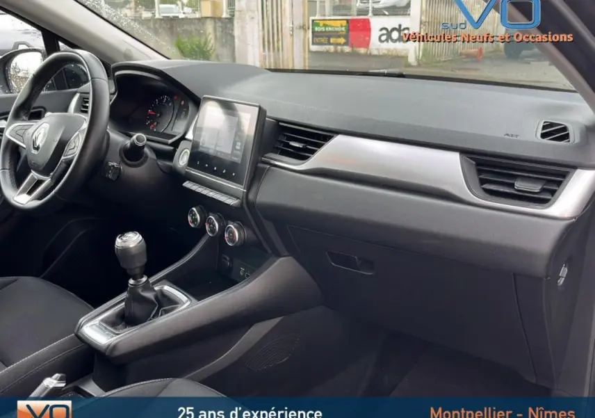 Intérieur côté passager du Renault Captur gris 2021, tableau de bord moderne avec écran tactile et boîte manuelle.