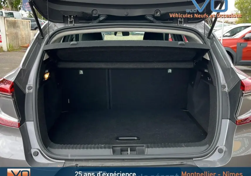 Coffre ouvert d'un Renault Captur gris 2021, vue arrière montrant l'espace de chargement vide et la tablette cache-bagages.