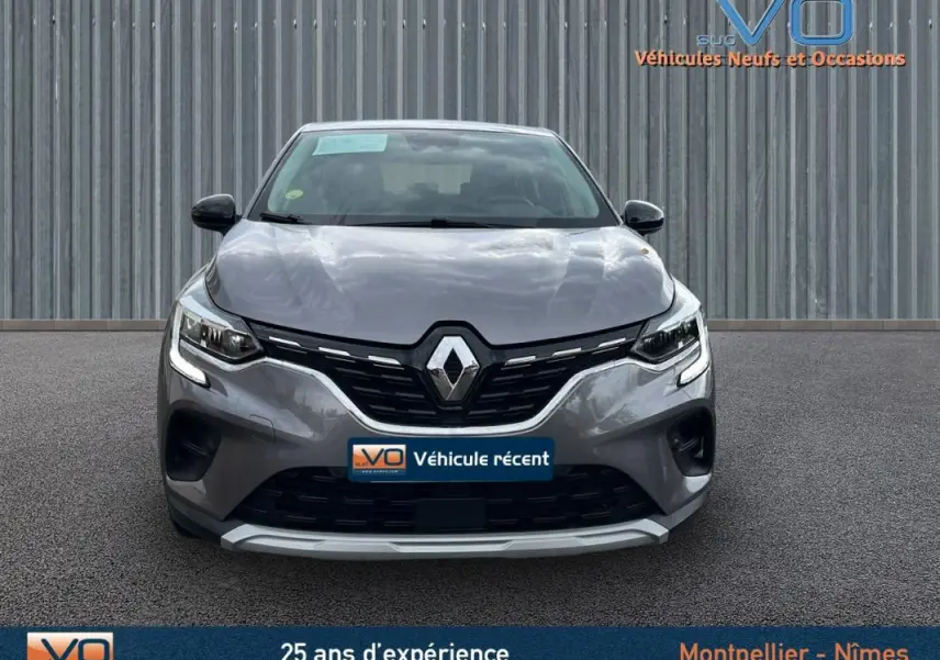 Vue frontale d'un Renault Captur gris 2021 avec calandre noire et feux LED allumés sur fond neutre.