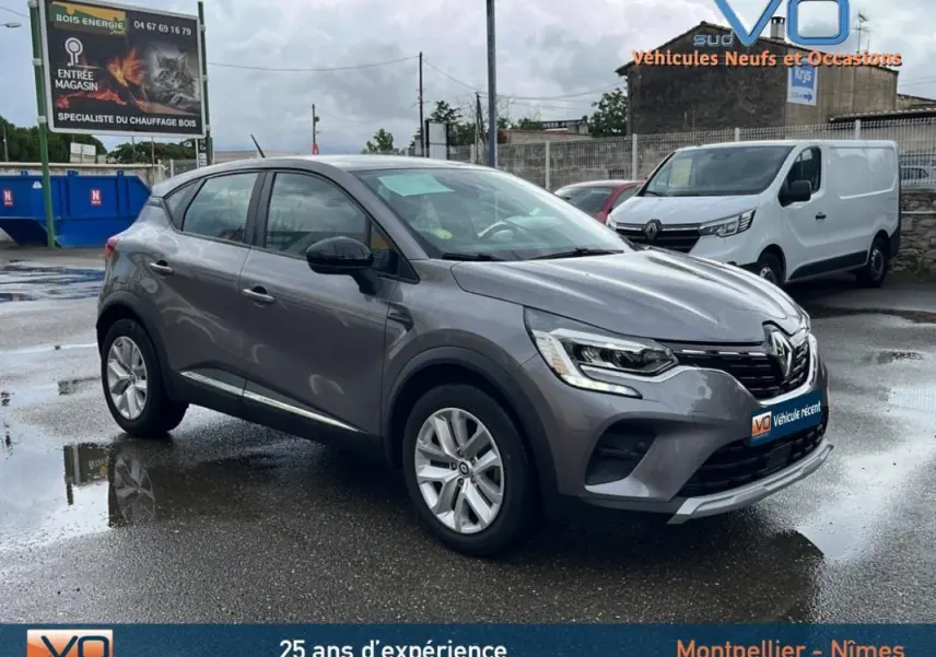 Renault Captur Blue dCi 115 Business gris vu en 3/4 avant droit sur parking humide avec feux allumés