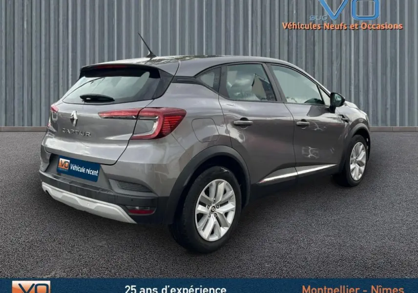 Vue 3/4 arrière droite d'un Renault Captur gris 2021 avec jantes alliage et feux arrière allumés.