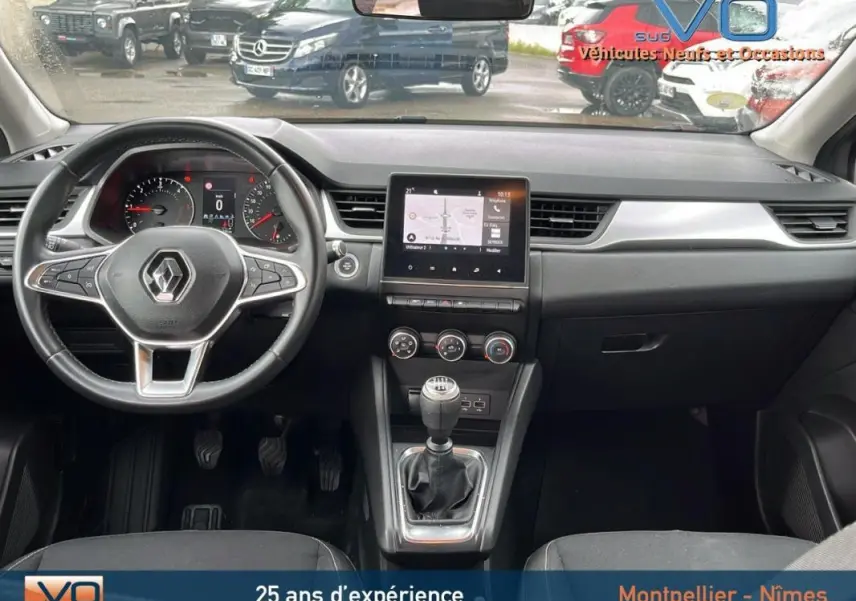 Vue intérieure avant du tableau de bord gris foncé du Renault Captur 2021 avec volant multifonction et écran tactile central.