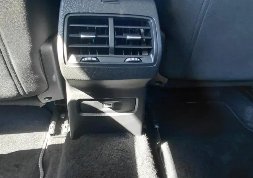 Vue rapprochée de la console arrière noire du Citroën C4 X hybride avec bouches d’aération et prise USB.