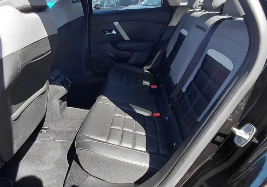 Vue intérieure côté droit des sièges arrière en cuir noir et gris d'une Citroën C4 X hybride 2025 avec accoudoir central.
