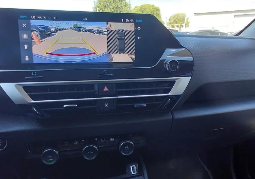 Vue intérieure du tableau de bord de la Citroën C4 X hybride noire 2025, avec écran tactile et commandes climatisation.