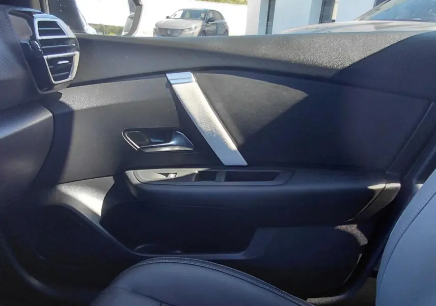 Vue intérieure côté droit de la porte et siège noir du Citroën C4 X hybride 2025 avec détails argentés.