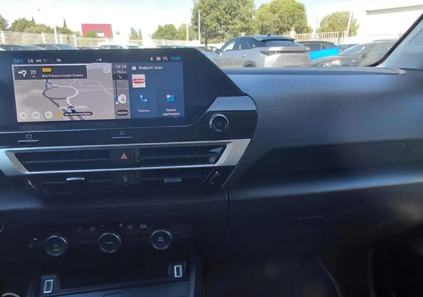 Vue intérieure du tableau de bord de la Citroën C4 X 2025, écran tactile central avec navigation et commandes climatisation.