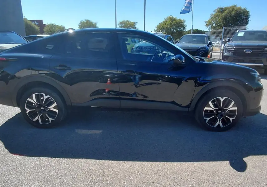 Vue de profil côté gauche d'une Citroën C4 X noire 2025 avec jantes alliage 17 pouces sur parking extérieur.