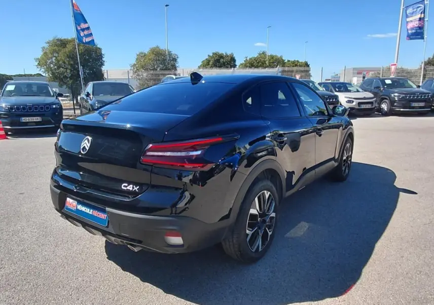 Vue 3/4 arrière droite d'une Citroën C4 X noire 2025 avec jantes alliage 17 pouces et toit ouvrant panoramique.