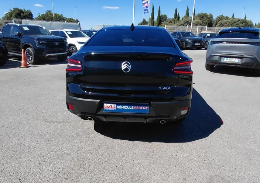 Vue arrière d'une Citroën C4 X noire 2025 avec feux LED et double sortie d'échappement visible en parking.