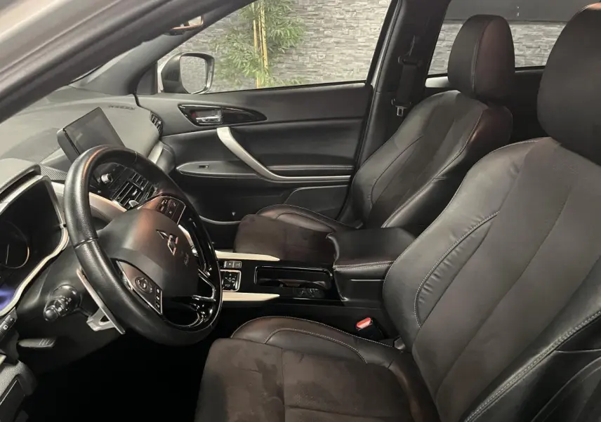 Intérieur avant du Mitsubishi Eclipse Cross 2022, sièges en cuir noir et tableau de bord avec écran tactile visible côté gauche.