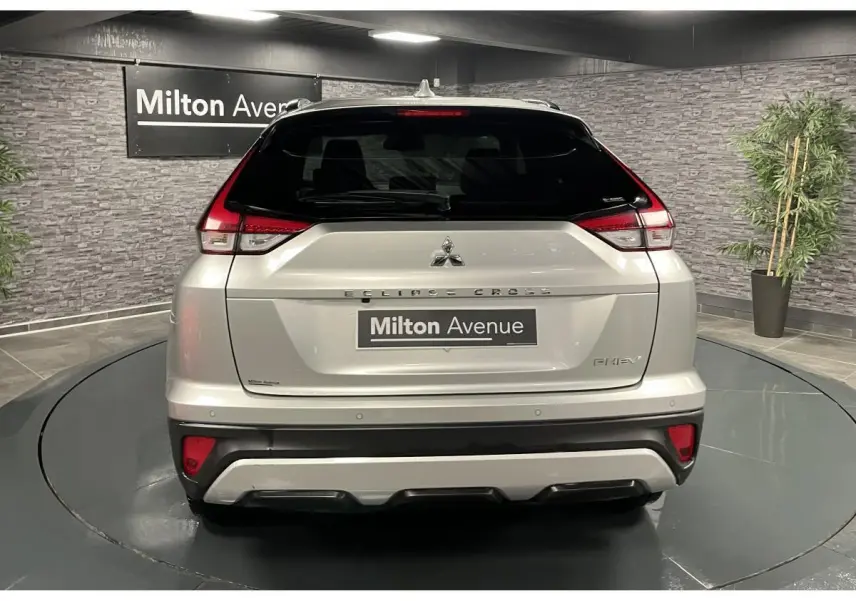 Vue arrière du Mitsubishi Eclipse Cross gris métallisé avec feux LED et logo PHEV visible en intérieur showroom
