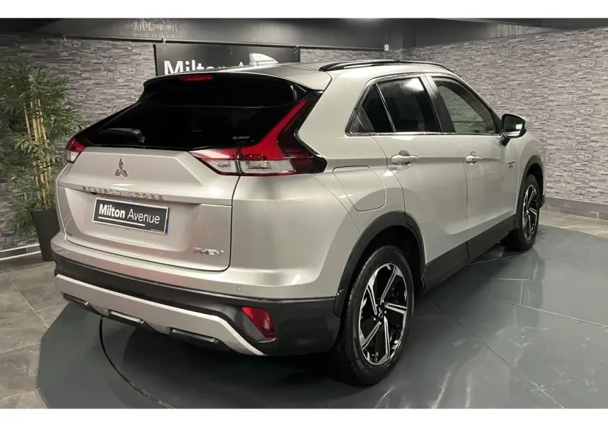Vue 3/4 arrière droite du Mitsubishi Eclipse Cross gris métallisé avec toit noir et jantes alliage bi-ton dans un showroom.