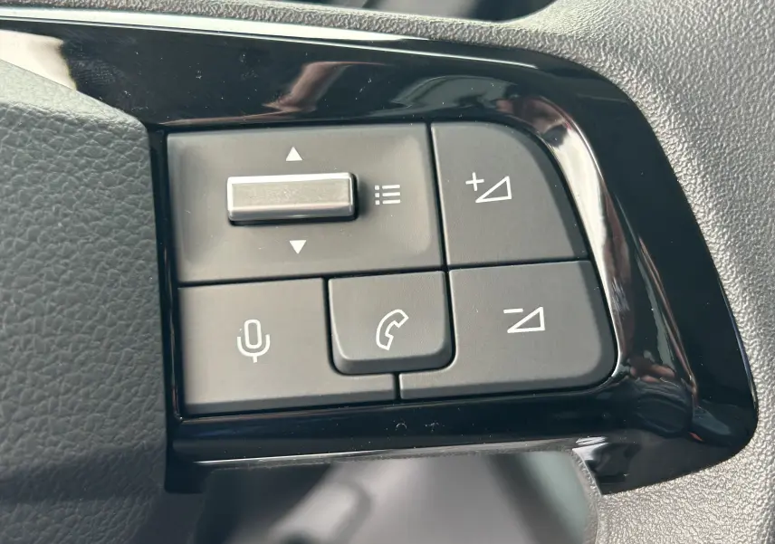 Gros plan sur les commandes au volant noir brillant du Citroën Berlingo Fourgon blanc, avec boutons de volume et téléphone.