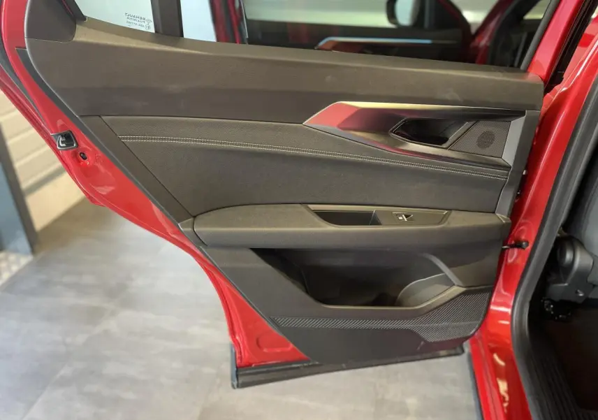 Gros plan sur la porte arrière gauche rouge du Renault Rafale 2025 avec garniture noire et surpiqûres argentées.