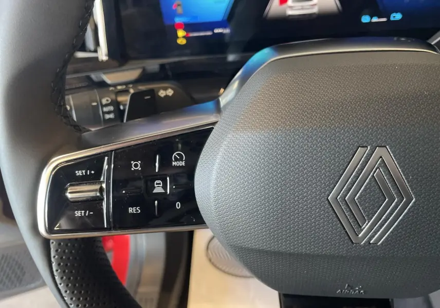 Gros plan sur le volant gris texturé avec commandes intégrées du Renault Rafale 2025, intérieur moderne et écran digital.