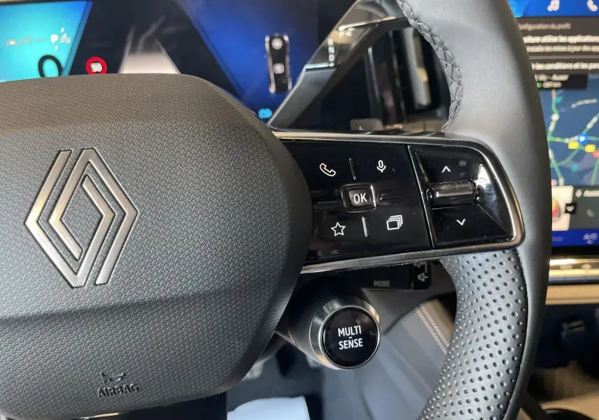 Gros plan sur le volant noir perforé de la Renault Rafale 2025 avec commandes et bouton Multi-Sense visible.