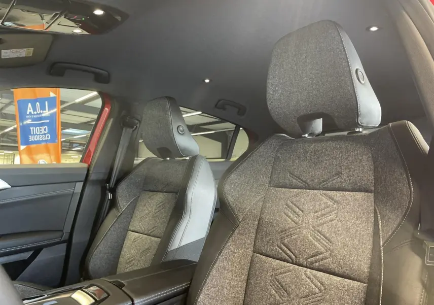 Vue intérieure sur les sièges avant gris textile embossé et accoudoir central noir du Renault Rafale rouge 2025.