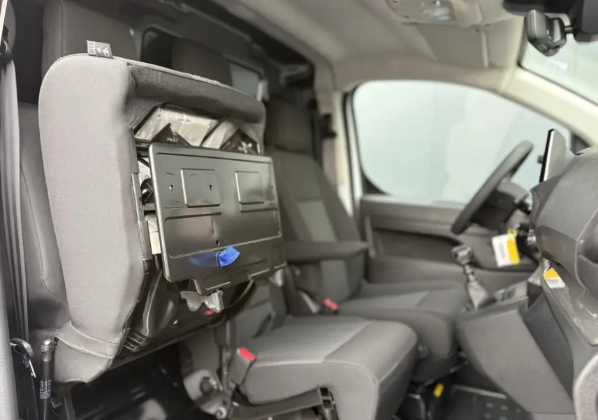 Vue intérieure côté droit du Peugeot Expert Fourgon 2025, banquette passager rabattue avec tablette écritoire visible.