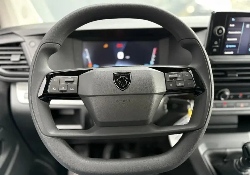 Vue rapprochée du volant noir du Peugeot Expert Fourgon 2025 avec commandes intégrées et logo lion central.