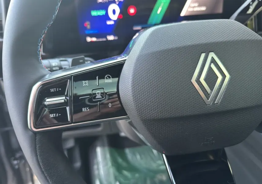 Gros plan sur le volant multifonctions noir avec logo Renault et commandes intégrées du Renault Austral New 200 Esprit Alpine.