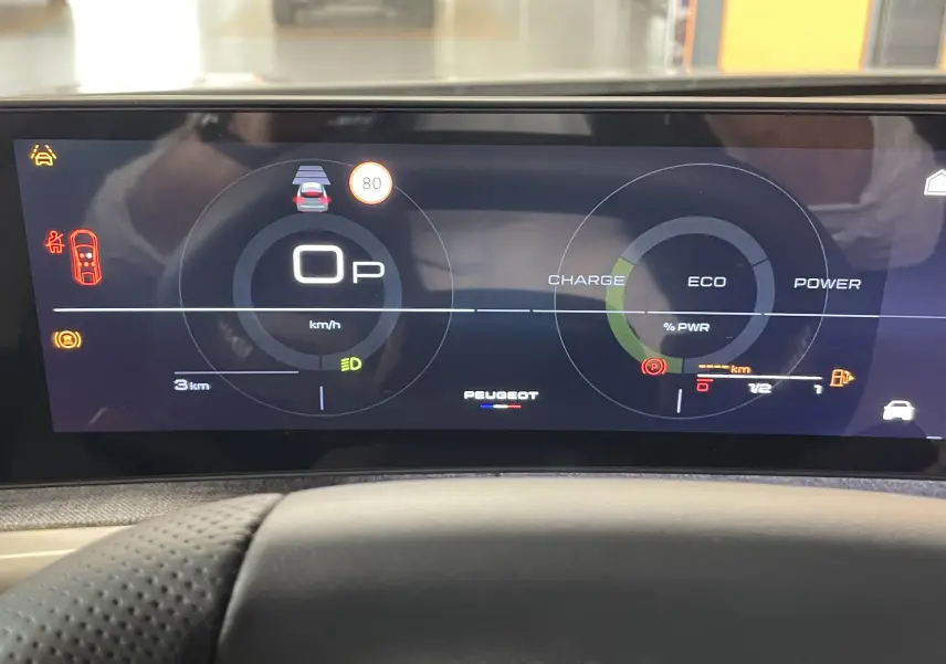 Vue intérieure du tableau de bord numérique du Peugeot 3008 Hybrid 2026, affichage digital avec indicateurs de vitesse et charge.