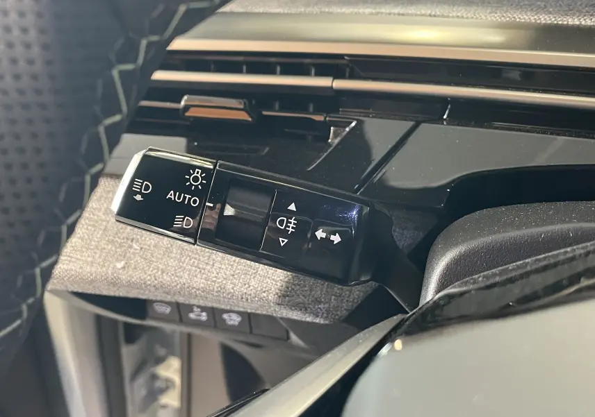 Gros plan sur la commande des feux et clignotants du Peugeot 3008 Hybrid 145, finition GT Exclusive, intérieur tissu gris.