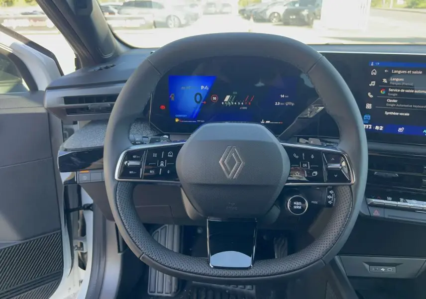Vue intérieure centrée sur le volant multifonctions de la Renault Clio blanc glacier avec tableau de bord numérique et écran tactile.