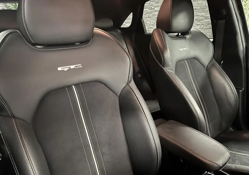 Gros plan sur les sièges avant noirs en cuir et suède avec logo GT Line brodé, intérieur d'une Kia Ceed 2023.