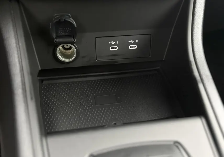 Gros plan sur la console centrale du Renault Captur 2025, montrant prises USB-C, prise 12V et chargeur induction noir.