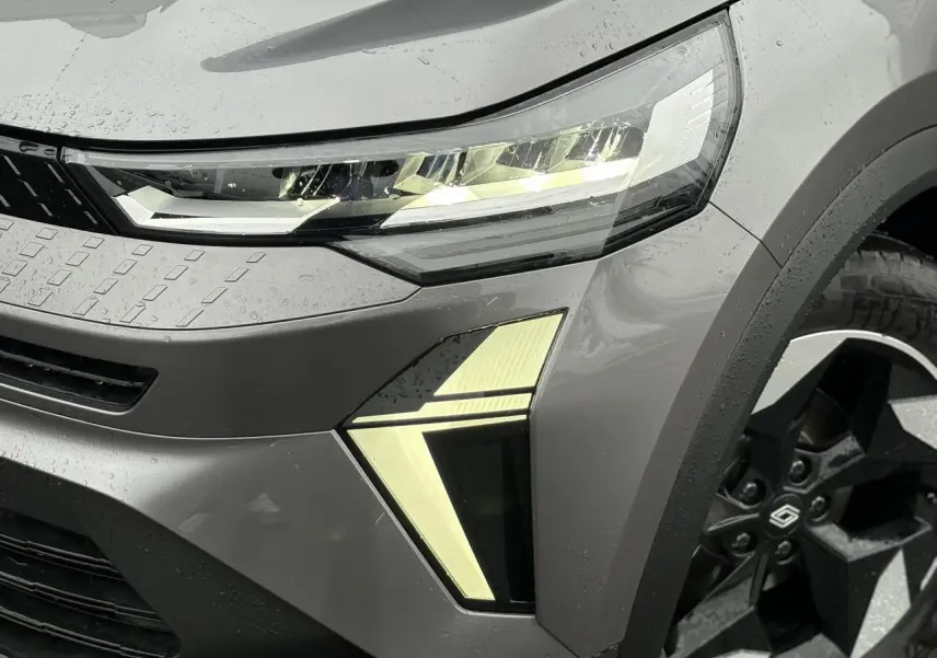 Gros plan sur l'avant droit gris Cassiopée du Renault Captur 2025, mettant en valeur le phare LED et la jante noire distinctive.