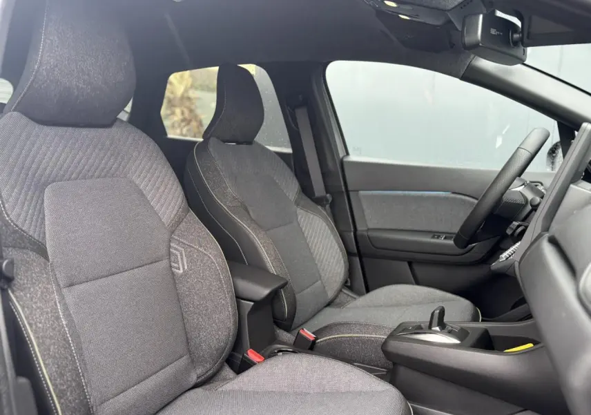 Vue intérieure côté droit du Renault Captur 2025, sièges gris avec console centrale et volant textile.