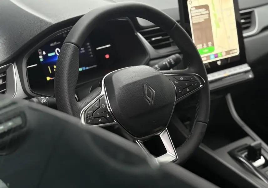 Vue rapprochée du volant noir et du tableau de bord numérique du Renault Captur 2025 avec écran tactile vertical.