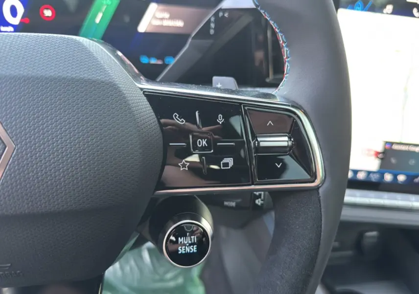 Gros plan sur le volant cuir multifonctions du Renault Austral New 200 Esprit Alpine, avec bouton Multi Sense éclairé.