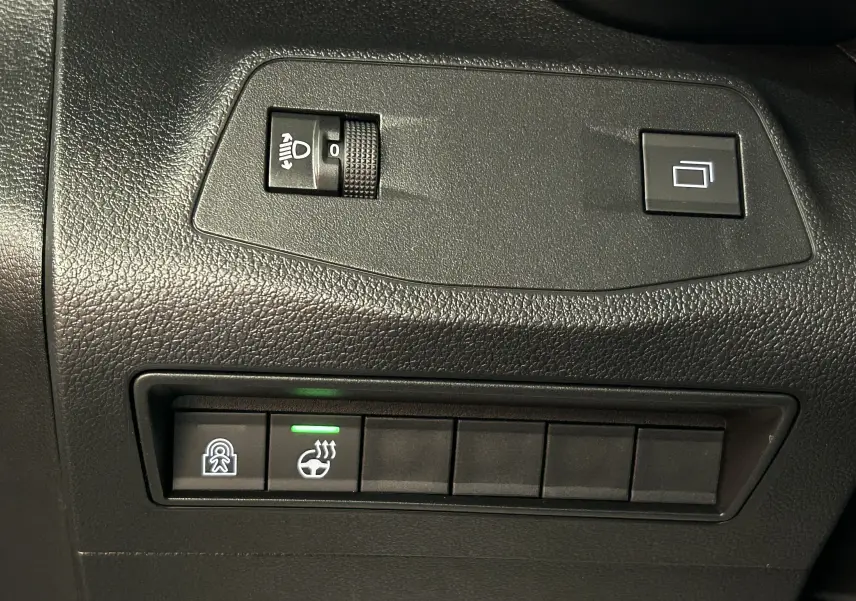 Gros plan sur les commandes noires du tableau de bord du Citroën Berlingo Multispace, avec bouton de chauffage de volant allumé.