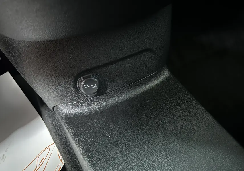 Prise 12V noire sur console centrale en plastique texturé noir du Citroën Berlingo Multispace gris acier.