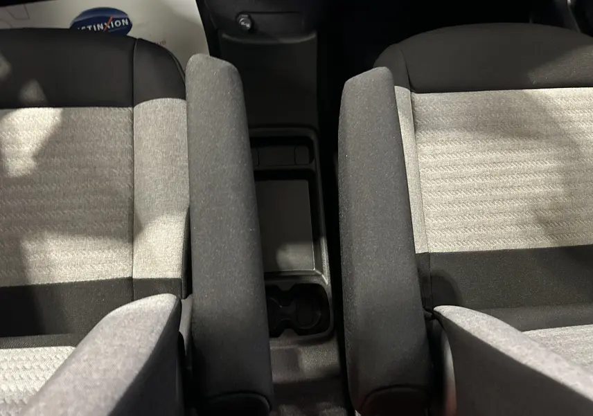 Vue plongeante sur les sièges avant gris clair et noir du Citroën Berlingo Multispace avec accoudoirs centraux relevés.