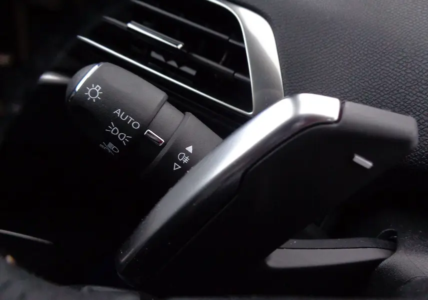 Gros plan sur la commande des feux et la palette de changement de vitesse côté gauche du Peugeot 3008 gris 2023.