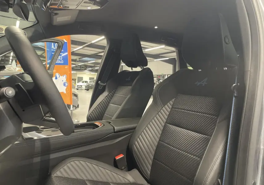 Vue intérieure côté conducteur du Renault Austral 2025 avec sièges noirs en cuir et logo Alpine brodé sur les appuie-têtes.