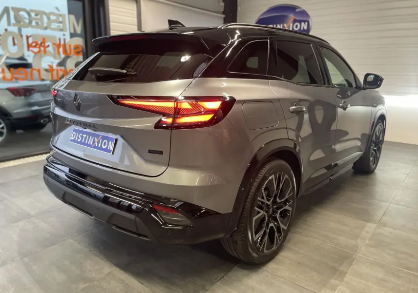 Vue 3/4 arrière droite du Renault Austral 2025 gris Schiste métallisé avec toit noir étoilé et feux arrière allumés.