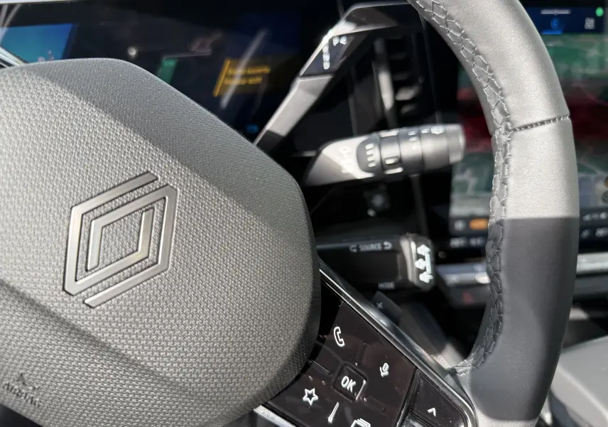 Détail du volant et commandes du Renault Austral Full Hybrid 2026, avec affichage numérique en arrière-plan.