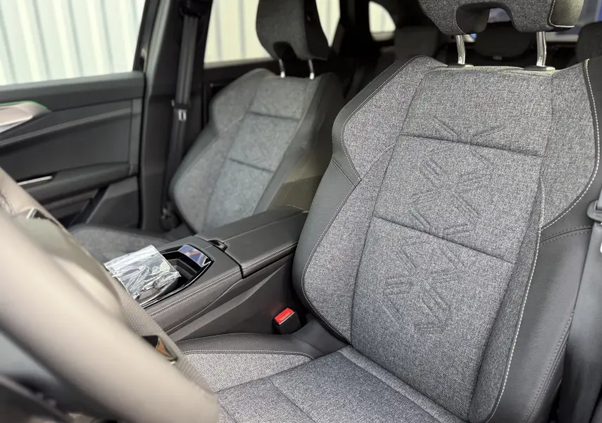 Intérieur du Renault Austral 2026, vue rapprochée des sièges avant en tissu gris avec surpiqûres et cuir noir.