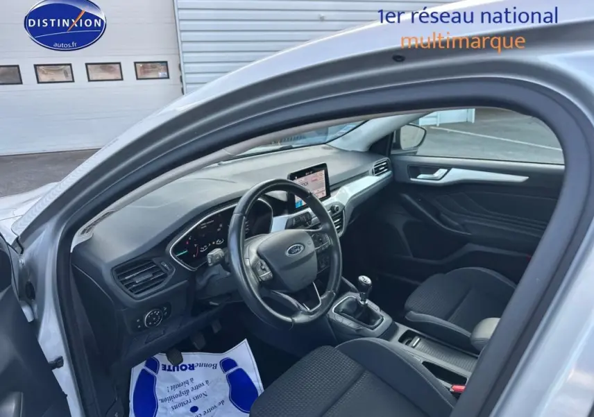 Intérieur avant gauche d'une Ford Focus gris clair 2019, avec tableau de bord moderne et boîte manuelle visible.