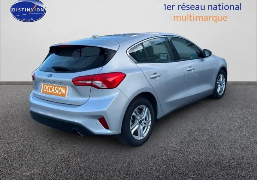 Vue 3/4 arrière droite d'une Ford Focus gris clair 2019 avec jantes alliage et feux arrière rouges distinctifs.