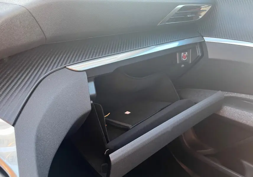 Intérieur du Peugeot 3008 2023, vue sur la boîte à gants ouverte côté passager avec finition carbone et détails noirs.